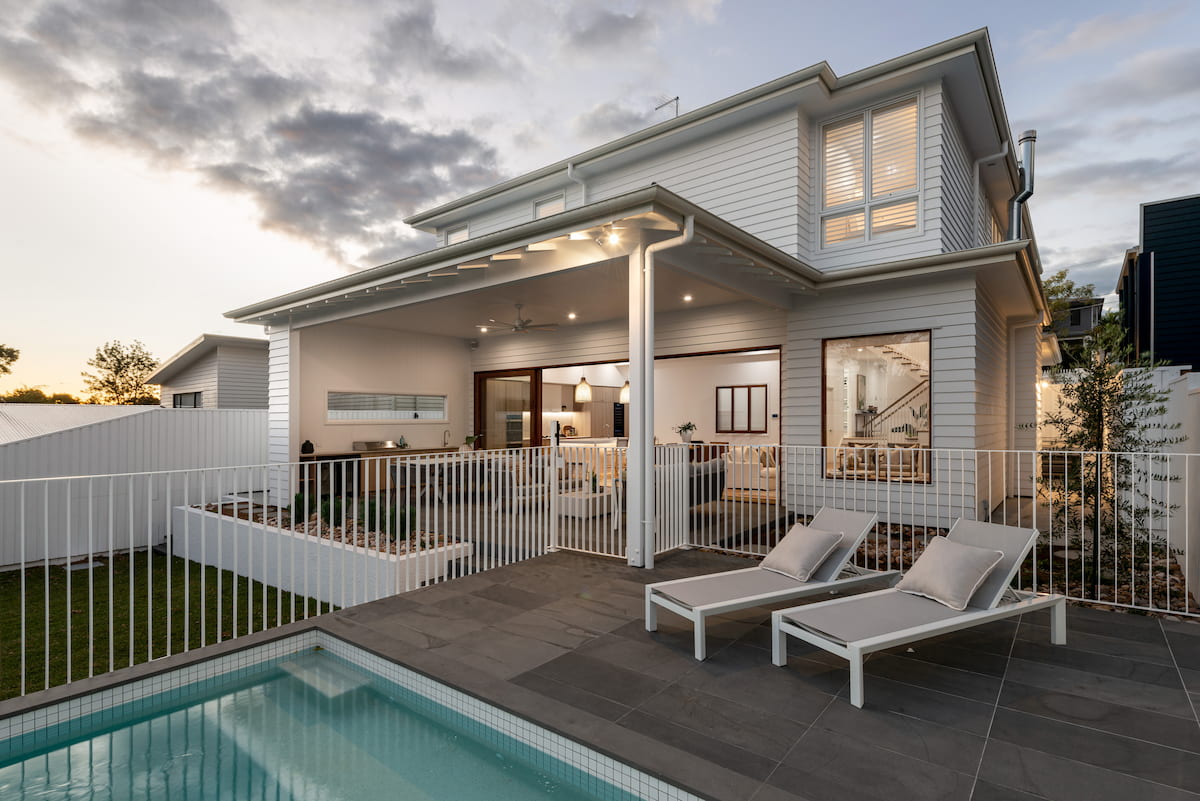 Rear of white weatherboard home at dusk with pool and covered alfresco