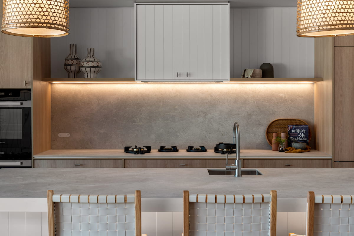 Kitchen with stone splashback, oak cabinetry and rattan pendant lights